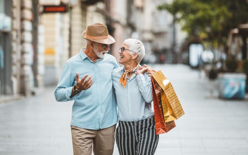 a man and woman holding shopping bags while walking